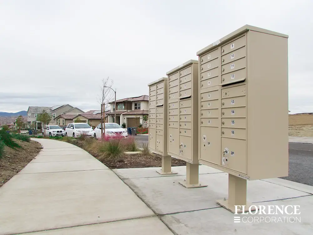 three florence vital&trade; cluster box units in sandstone installed facing sidewalk near curb in residential neighborhood in late fall early spring near white parked cars