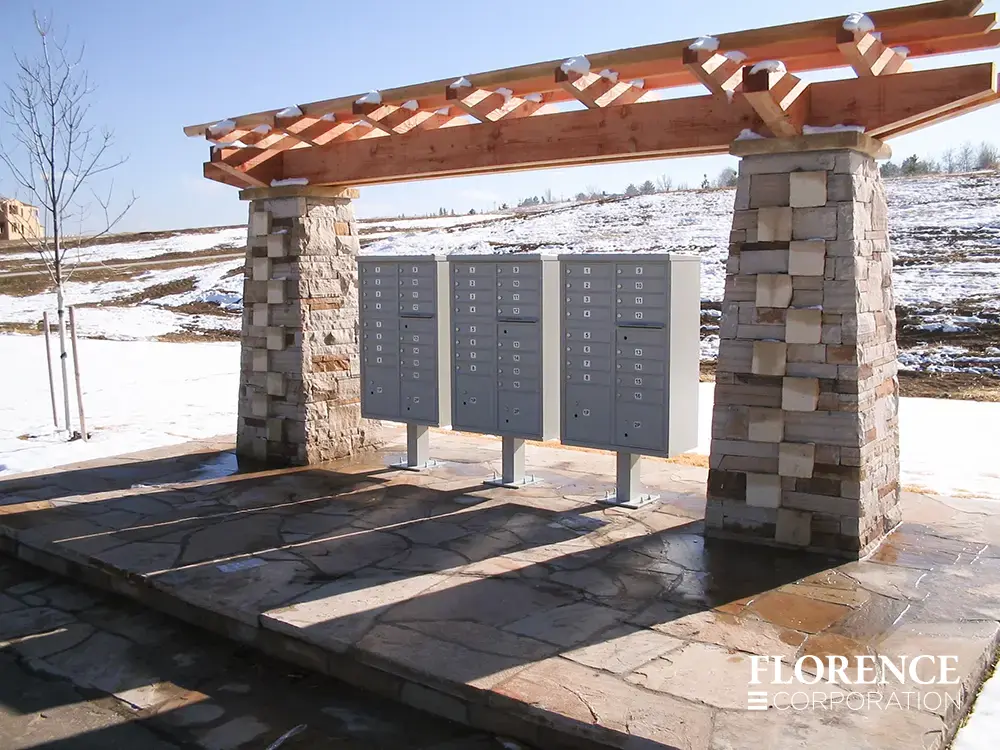 vital&trade; cluster box units in postal grey installed outdoors under rock and wood decorative pergola on a snowy winter day