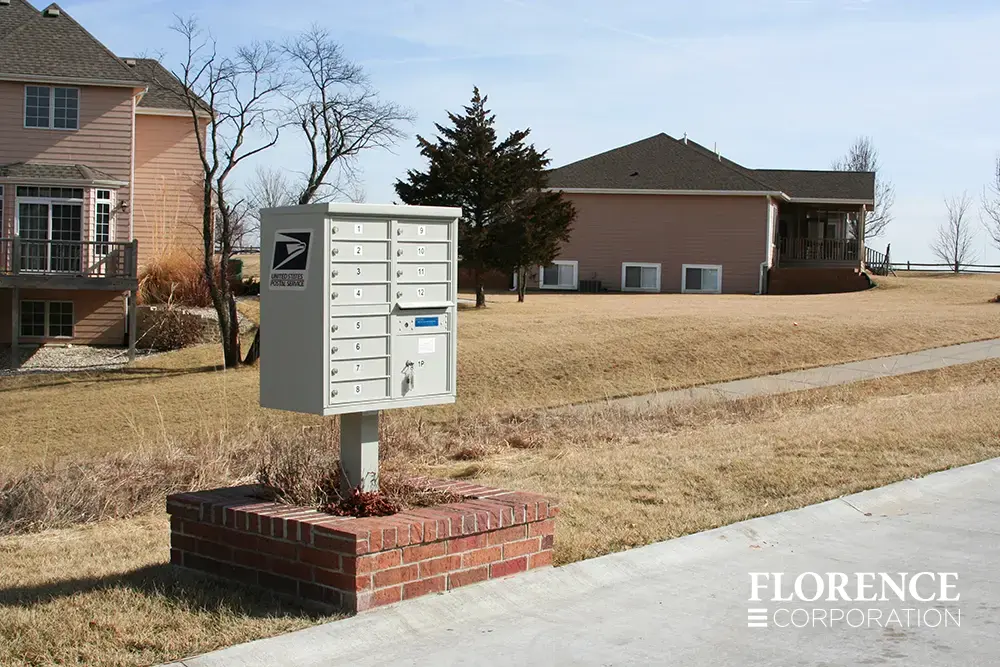 vital&trade; cluster box unit in postal grey installed in new single-family development community with decorated brick stone base and shrubbery in late fall