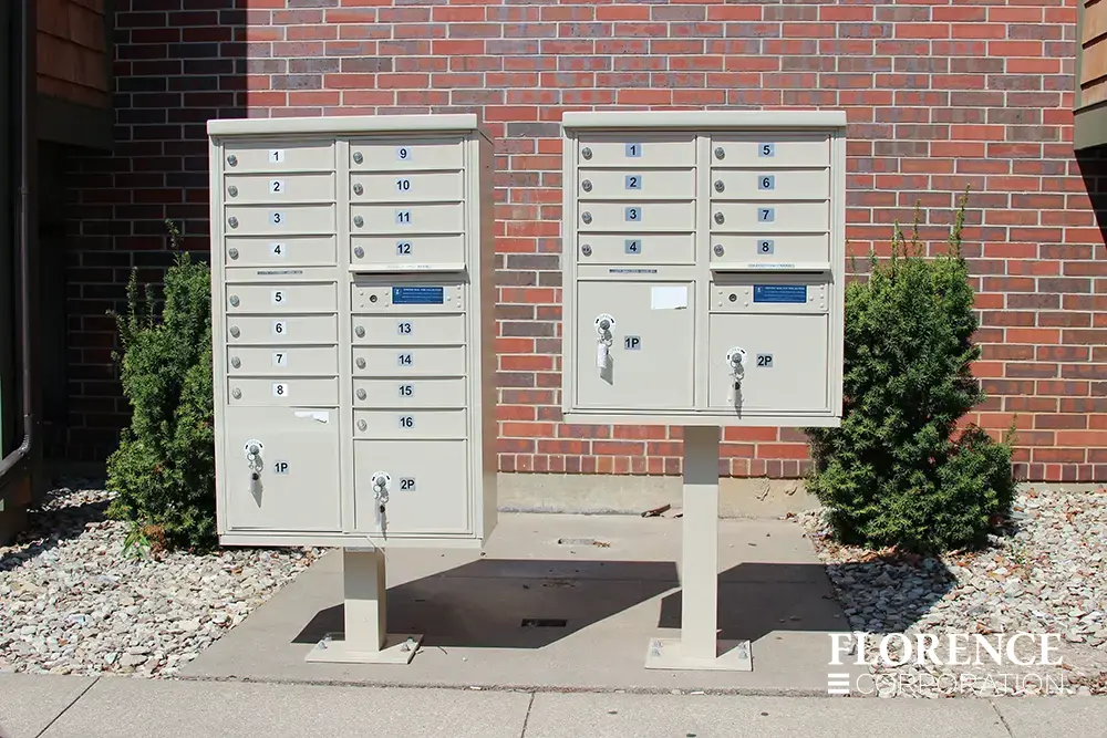 two different vital&trade; cluster box units in sandstone installed along sidewalk near brick building entrance
