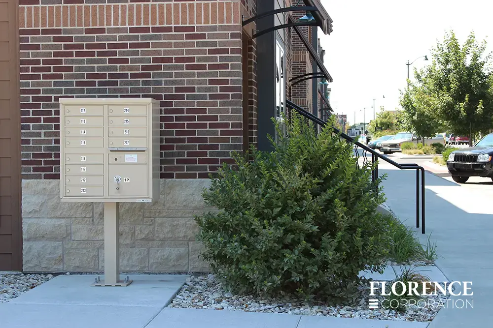 vital&trade; cluster box unit in sandstone installed outdoor near red brick town home building