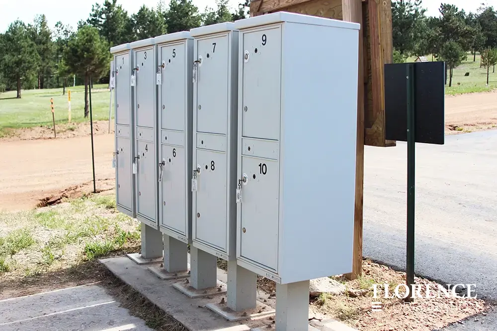 valiant&trade; outdoor parcel lockers in postal grey installed outdoor near green park and black tar parking lot