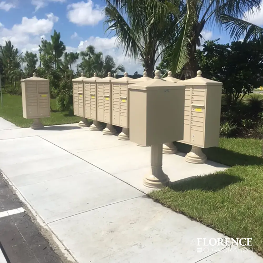 vogue&trade; accessories on vital&trade; cluster box units all in sandstone installed together near the sidewalk in a sunny neighborhood with blue skies and palm trees in the background