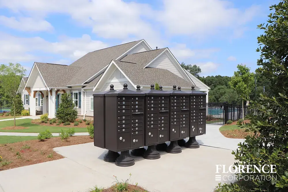 vogue&trade; accessories on vital&trade; cluster box units in dark bronze installed back-to-back near hoa community recreation center with outdoor pool