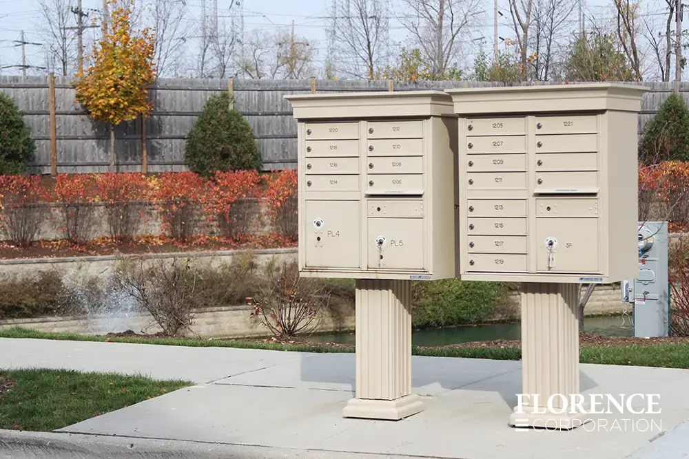 vogue&trade; accessories on vital&trade; cluster box units in sandstone installed on curbside in the fall with orange leaves in front of canal