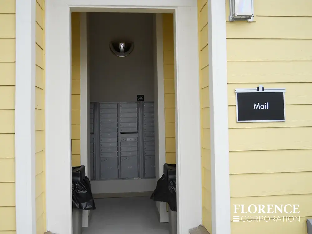 recessed mounted versatile&trade; 4C mailboxes in silver speck installed in open air mailroom in building with yellow siding