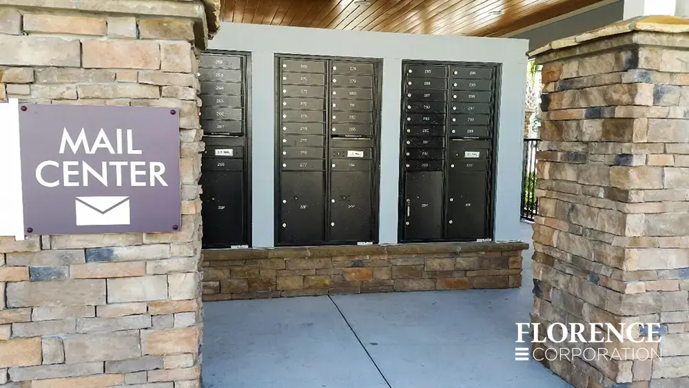 recessed mounted versatile&trade; 4C mailboxes in black mounted on stone foundation under covered open air mail center