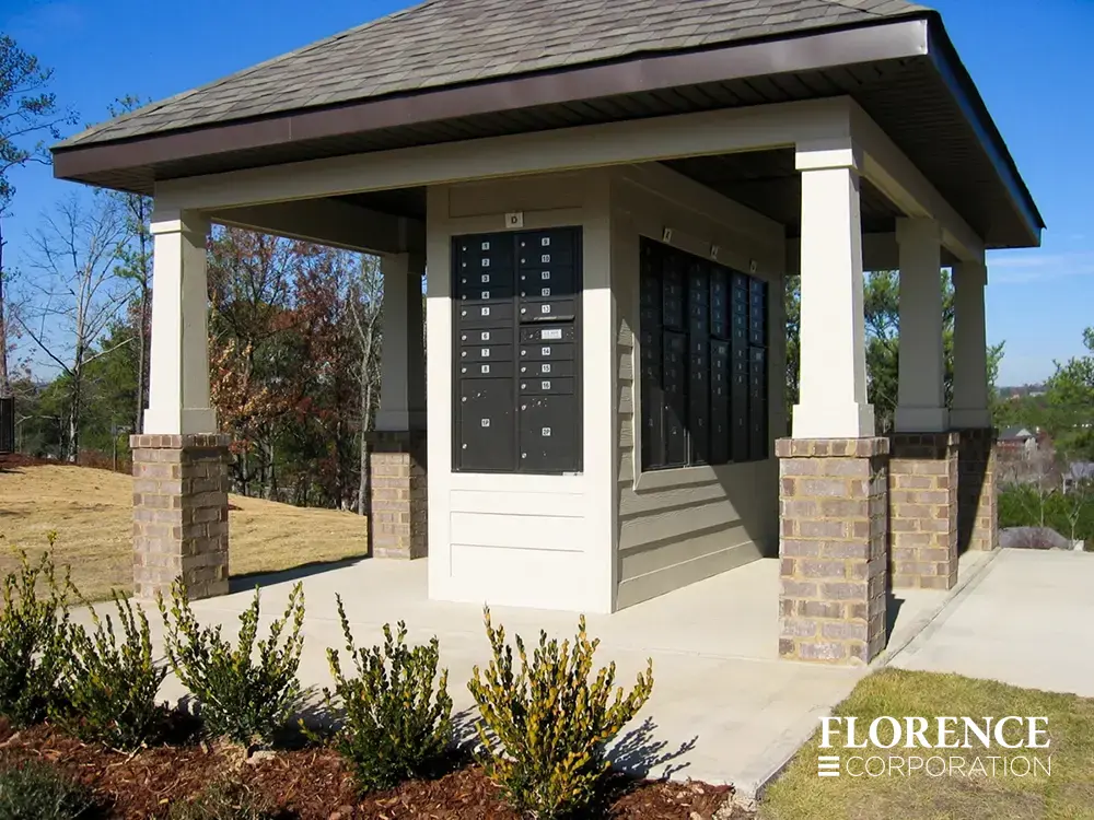 black recessed mounted versatile&trade; 4C mailboxes in cream wall under roof of shingled pavilion with brick and wood pillars