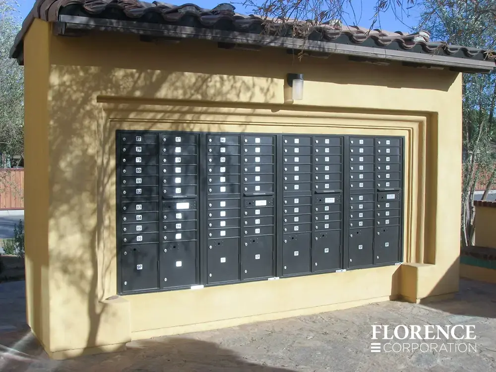 recessed mounted versatile&trade; 4C mailboxes in black installed in yellow concrete fixture in parking lot of multifamily residential area