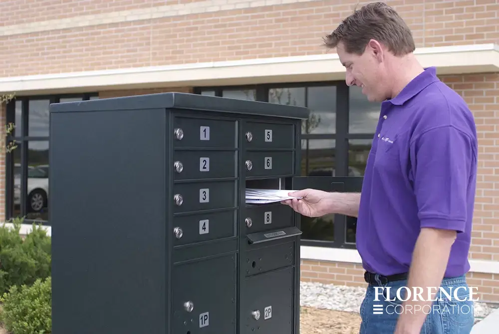 florence mailboxes vital&trade; cluster box unit in black installed outside of brick commercial building with white man with short hair in purple shirt retrieving the mail