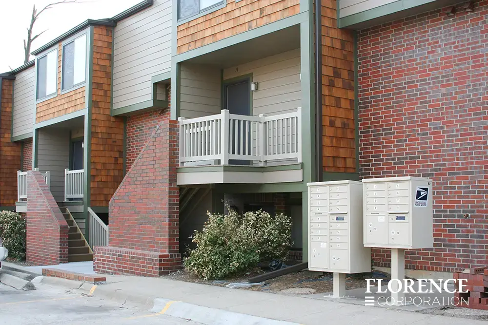 vital&trade; cluster box units in sandstone installed with two mailbox configurations directly outside of brick apartment building complex