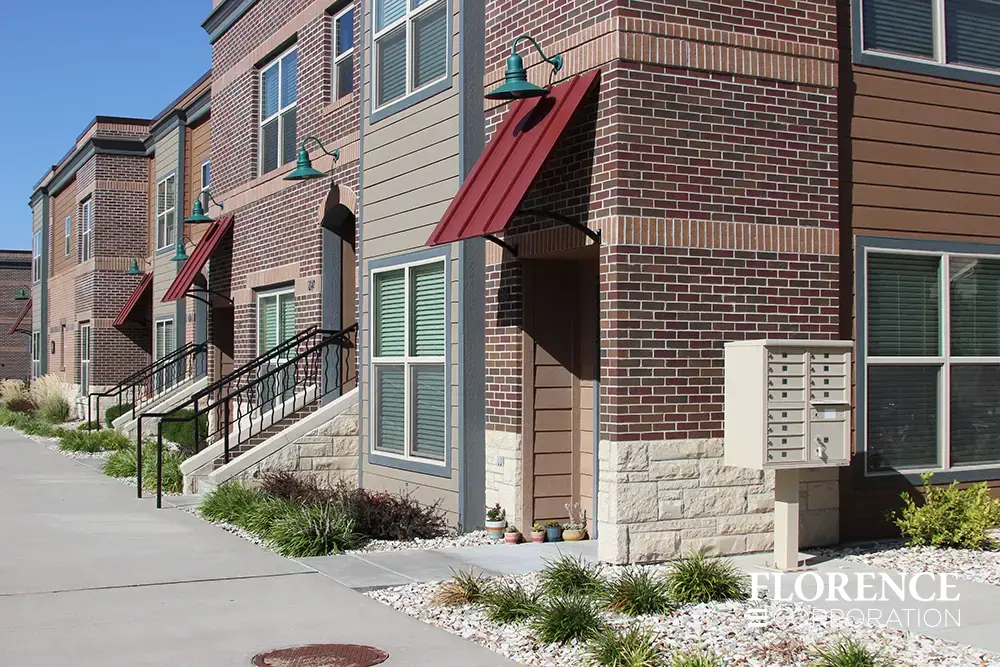 Single vital&trade; cluster box unit install in sandstone outside brick townhome building with greenery and large windows