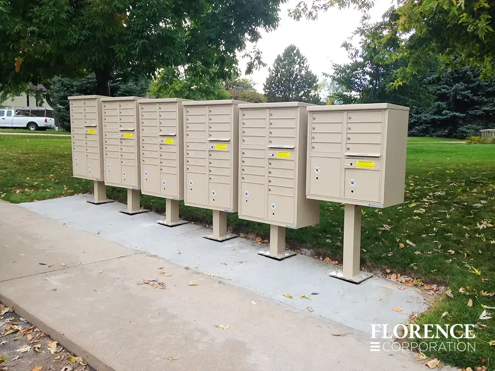 vital&trade; cluster box units in sandstone installed six in a row on cement patch near grassy common area near sidewalk on a fall day