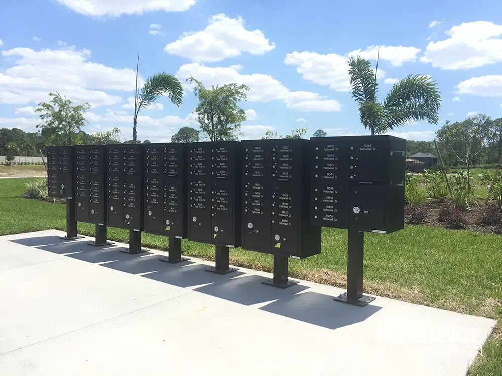 vital&trade; cluster box units in dark bronze with custom engraving installed near grassy common area in sunny weather surrounded by palm trees