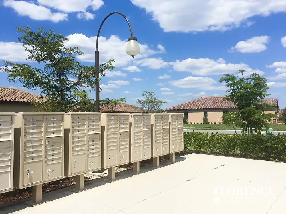 vital&trade; cluster box units in sandstone installed in a row under street lamp near green landscaping
