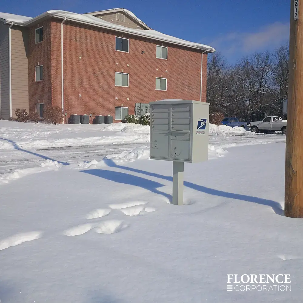 vital&trade; cluster box units in postal grey outdoor in the snow during a winter day near red brick apartment building