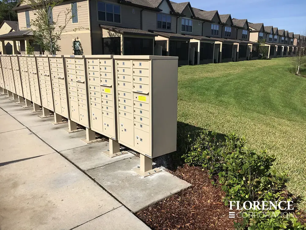 vital&trade; cluster box units in sandstone installed on large concrete slab near cottage chic apartment community with green landscaping and cut grass