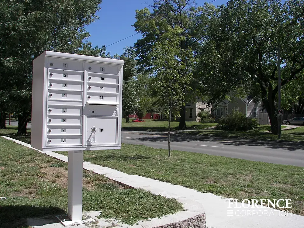 Single vital&trade; cluster box unit in white near steps to townhomes with green grass, large trees and single family homes across the street