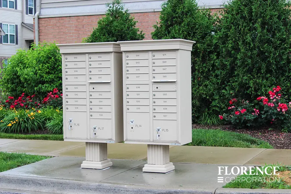 vogue-CBU-Accessories_043 a pair of vogue™ accessories on vital™ cluster box units in sandstone installed in multifamily community on a rainy day surrounded by lush landscaping