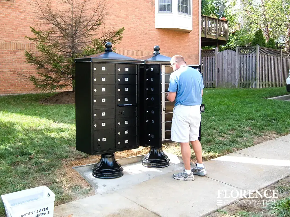 vogue-CBU-Accessories_049 vogue™ accessories on vital™ cluster box units in black installed in townhome community along side walk with master access door open while usps postal carrier delivers mail to residents