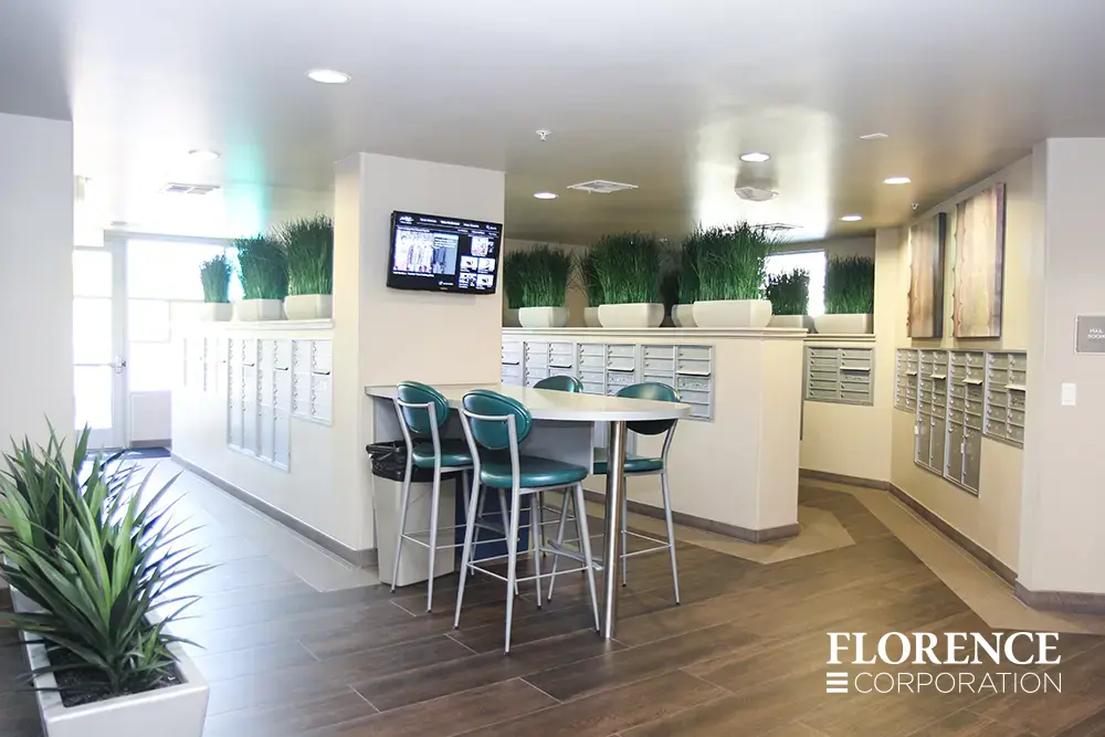 versatile-4C-indoor-install_015 Recessed mount versatile™ 4C mailboxes in silver speck installed in multifamily apartment mailroom with green plants, green stools and wall art décor