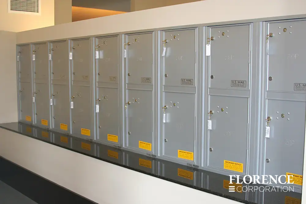 versatile-4C-indoor-install_024 Recessed mount versatile™ 4C parcel lockers in silver speck installed indoor on white wall with black stone ledge