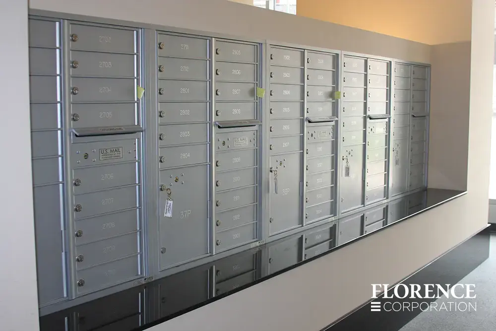 versatile-4C-indoor-install_025 Recessed mount versatile™ 4C parcel lockers in silver speck installed indoor in cream wall in apartment building over black stone ledge