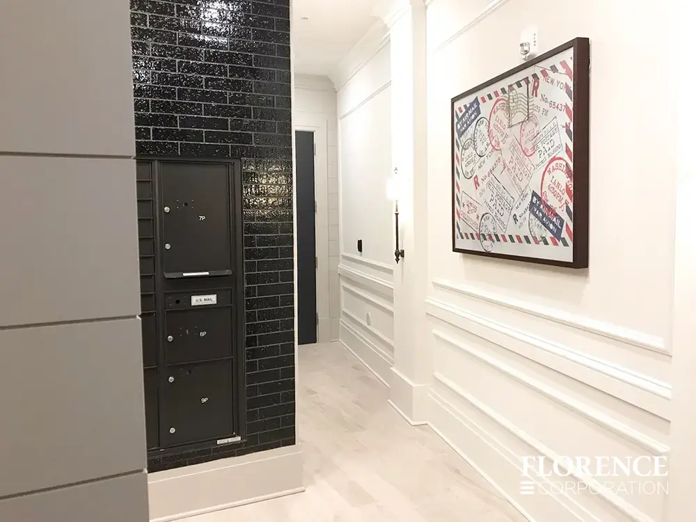 versatile-4C-indoor-install_032 Recessed mount versatile™ 4C parcel locker in black installed in modern mailroom area of apartment building with white walls and wall art