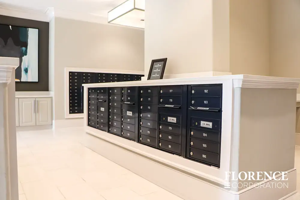 versatile-4C-indoor-install_034 Recessed mount versatile™ 4C mailboxes in black installed in modern chic well lit mailroom in multifamily apartment building with white cream walls , ceilings and floors