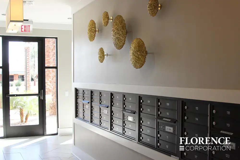 versatile-4C-indoor-install_040 Recessed mount versatile™ 4C mailboxes in black installed in luxe apartment building with tile floor, wall art and bright exit door.