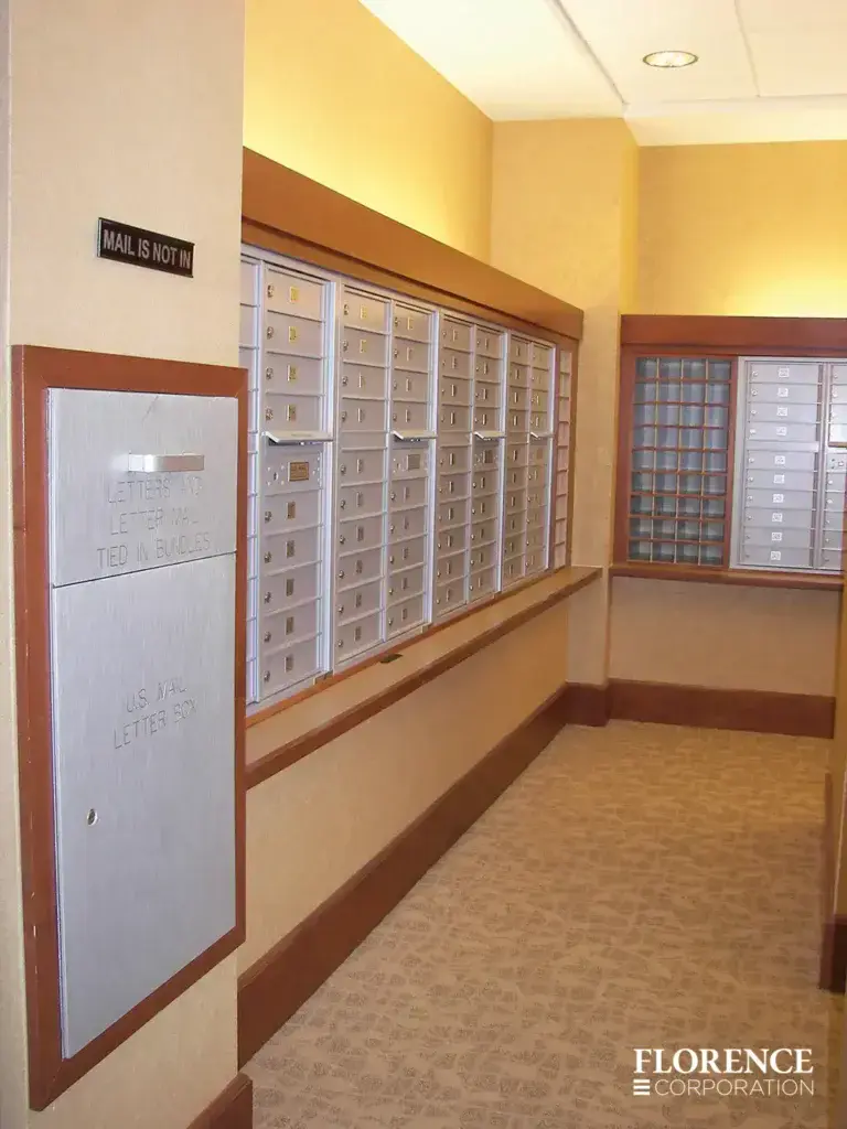 versatile-4C-indoor-install_047 Recessed mount versatile™ 4C mailboxes and collection box accessory all in silver speck installed in multifamily apartment mailroom with wood trim and wallpaper