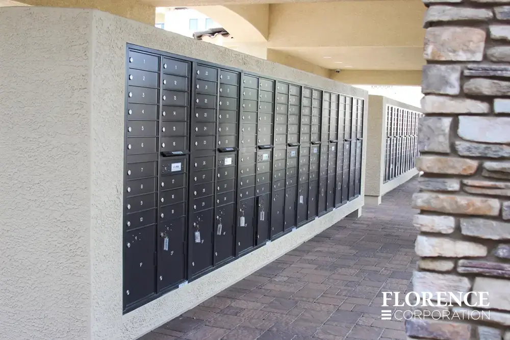 versatile-4C-recessed-indoor-14 multiple rows of recessed mounted versatile™ 4C mailboxes in black mounted in cream stucco under covered open air mail center