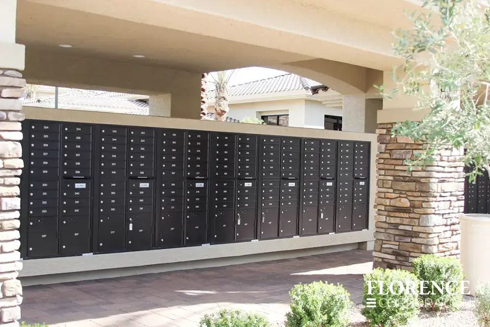 versatile-4C-recessed-indoor-17 recessed mounted versatile™ 4C mailboxes in black installed in large outdoor covered mailroom with rock exterior wall and green shrubbery landscaping