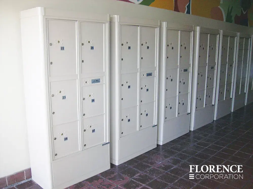 4C-versatile-surface-depot_018(2) several white versatile™ 4C parcel lockers installed in white freestanding depot cabinets on red tile floor against a white wall with colorful mural above